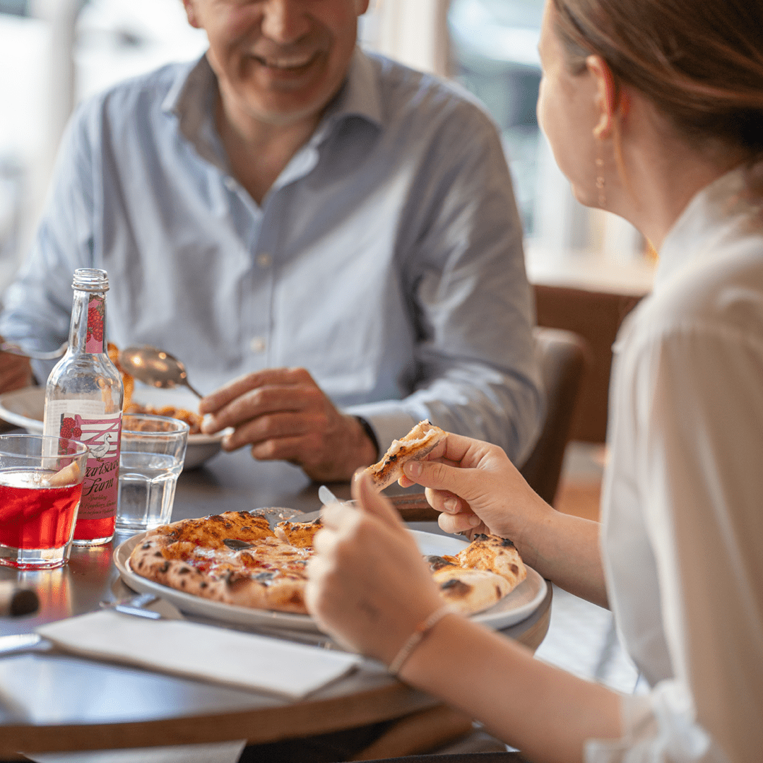 A couple happily shares a pizza at Leaven Pizza Hereford, Herefordshire, London, enjoying their meal together.